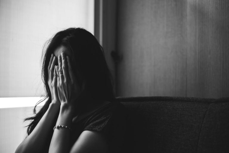 a woman sits with hands on her face feeling defeated and showing signs of benzo abuse